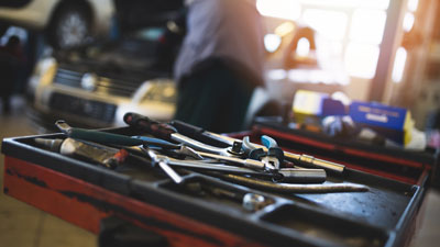 Werkzeuge eines KFZ-Mechatronikers, im Hintergrund Arbeit an einem Auto