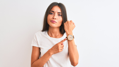 Junge Frau zeigt auf ihre Armbanduhr
